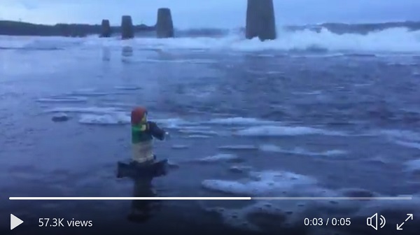 5s video showing a small wave washing away a person (in lego) talking a photo of the weather.